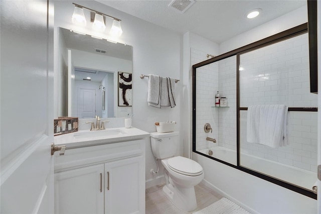 full bathroom with combined bath / shower with glass door, vanity, and toilet