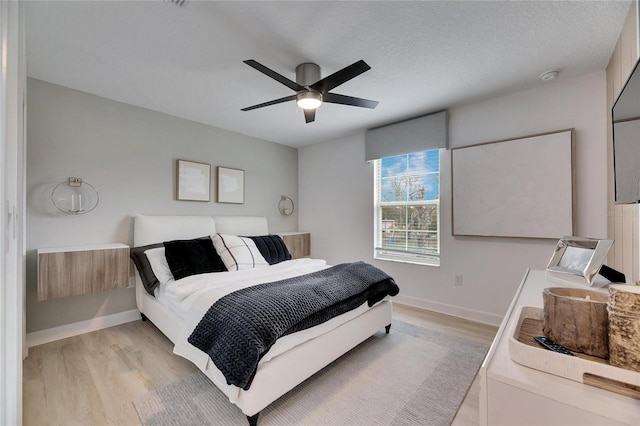 bedroom with ceiling fan, light hardwood / wood-style floors, and a textured ceiling