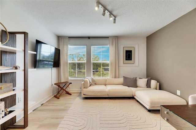 living room featuring a textured ceiling, light hardwood / wood-style floors, and rail lighting