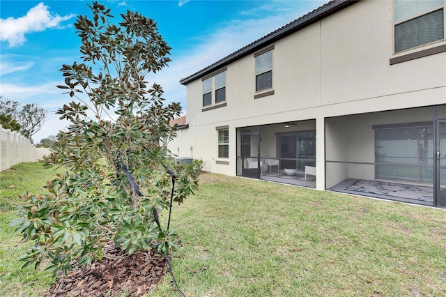 back of property featuring a sunroom and a lawn