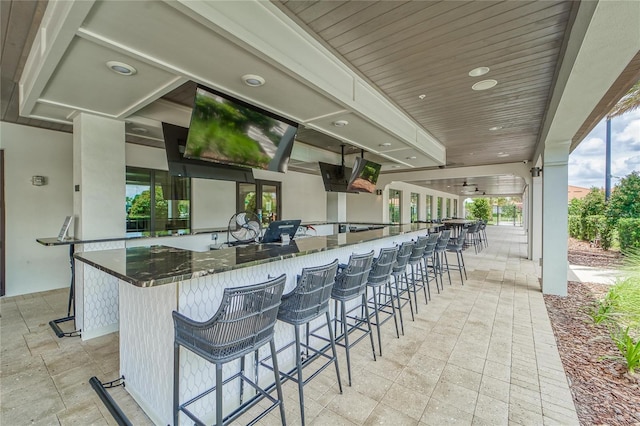 kitchen with a kitchen breakfast bar, wooden ceiling, and dark stone counters