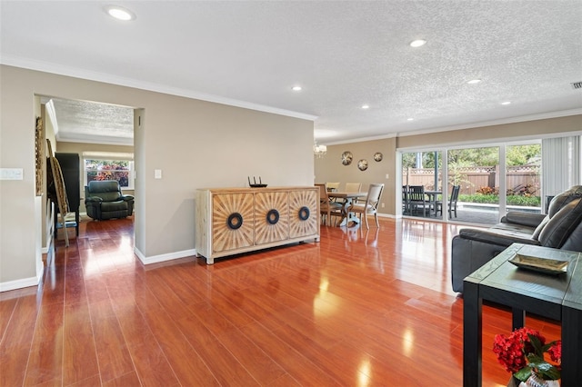 living room with hardwood / wood-style floors, a textured ceiling, and ornamental molding