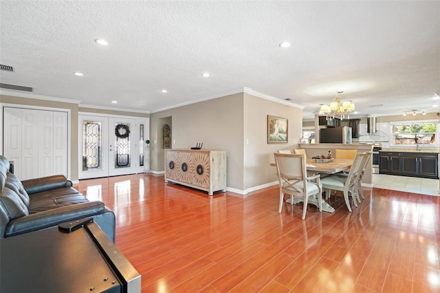 dining area with crown molding, french doors, a textured ceiling, and a notable chandelier