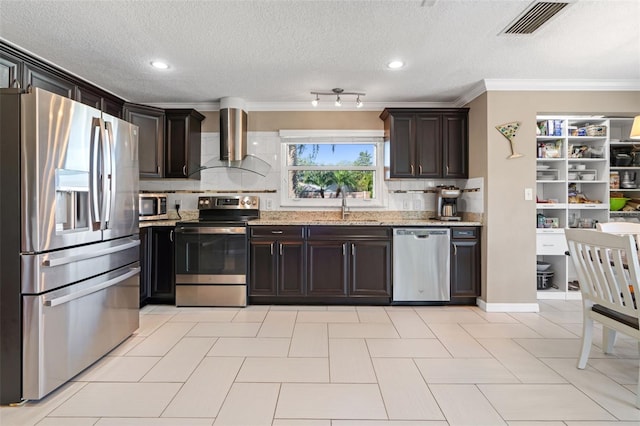 kitchen with sink, wall chimney exhaust hood, light stone counters, dark brown cabinets, and appliances with stainless steel finishes