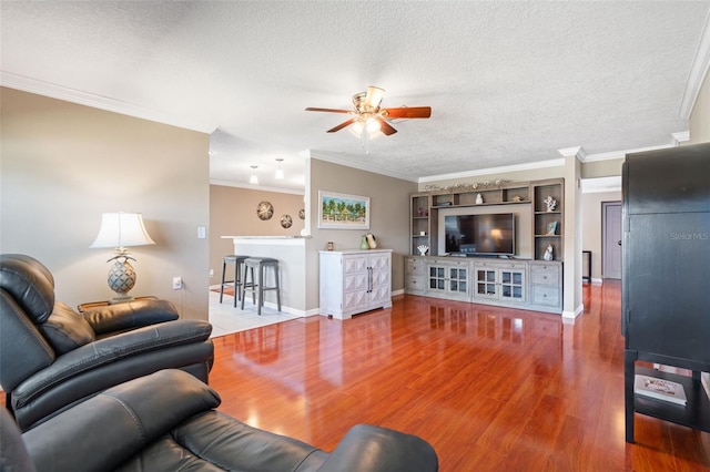 living room with wood-type flooring, a textured ceiling, ceiling fan, and ornamental molding