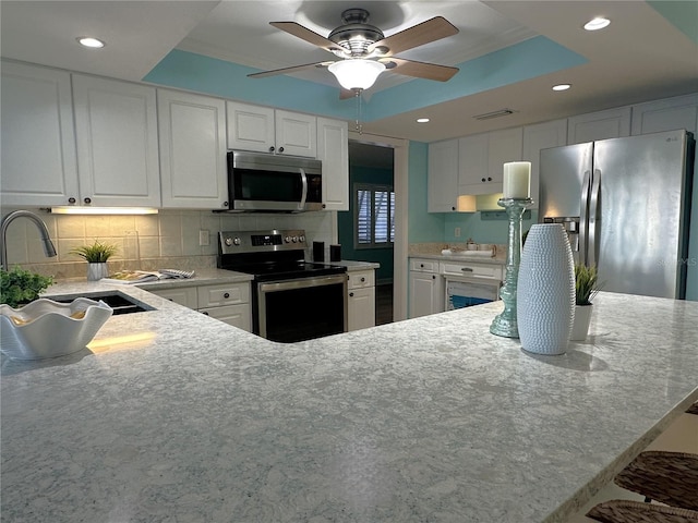 kitchen featuring white cabinets, sink, ceiling fan, kitchen peninsula, and stainless steel appliances