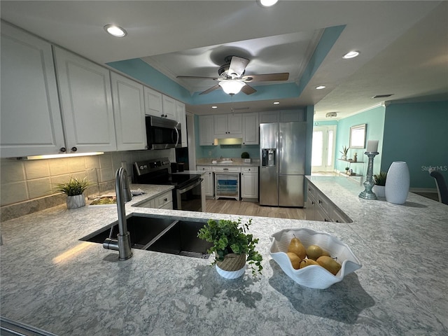 kitchen featuring white cabinetry, sink, a raised ceiling, wine cooler, and appliances with stainless steel finishes