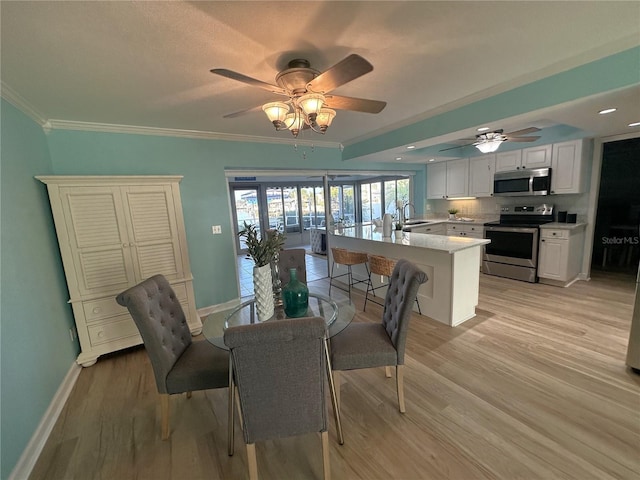 dining room featuring ceiling fan, ornamental molding, sink, and light hardwood / wood-style flooring