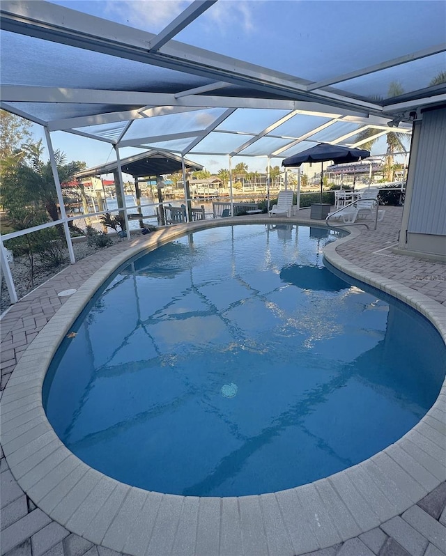 view of pool with glass enclosure and a patio area