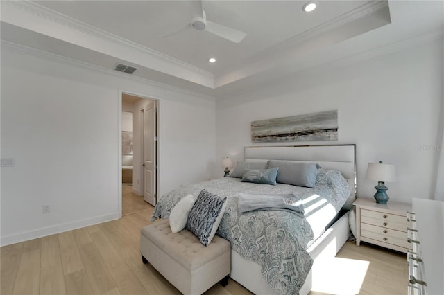 bedroom with ornamental molding, a raised ceiling, ceiling fan, light hardwood / wood-style flooring, and connected bathroom