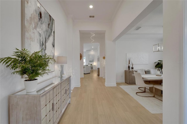 hallway featuring an inviting chandelier, light hardwood / wood-style flooring, and ornamental molding