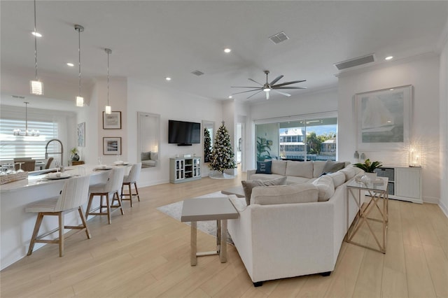 living room with a wealth of natural light, ceiling fan, sink, and light wood-type flooring