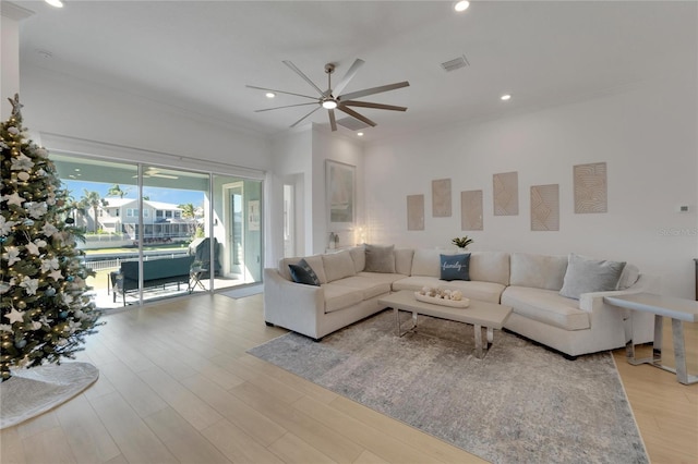 living room featuring light hardwood / wood-style flooring, ceiling fan, and crown molding