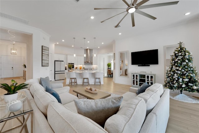 living room with ceiling fan, light hardwood / wood-style flooring, and ornamental molding