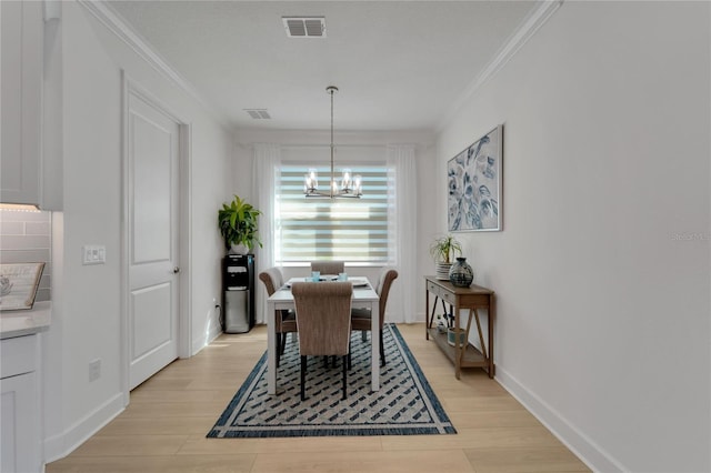 dining area with crown molding, light hardwood / wood-style flooring, and a notable chandelier