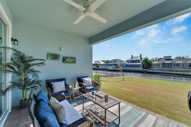 wooden terrace with a lawn, ceiling fan, a water view, and an outdoor hangout area