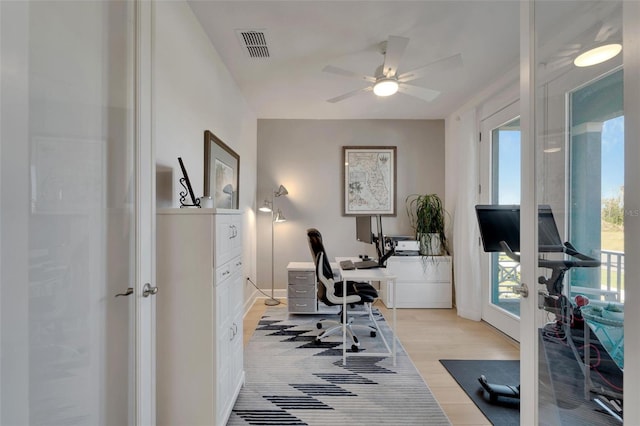 home office featuring light wood-style floors, ceiling fan, visible vents, and baseboards