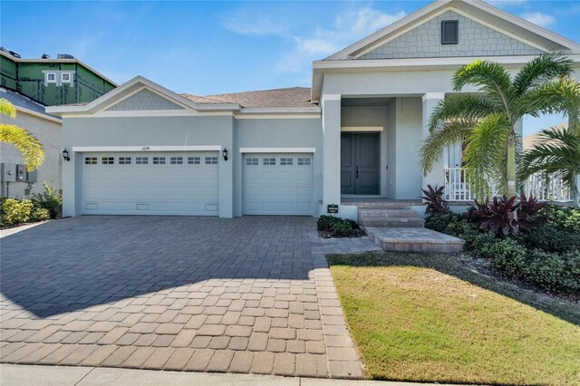 view of front facade with a garage, a shingled roof, decorative driveway, and stucco siding