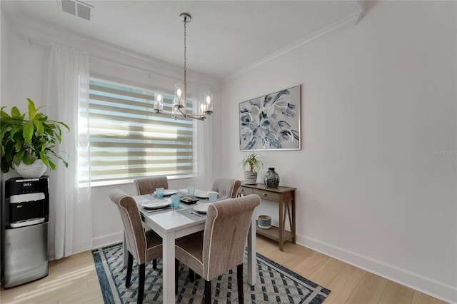 dining space with ornamental molding, visible vents, an inviting chandelier, light wood-style flooring, and baseboards