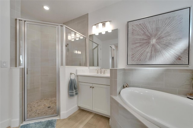 bathroom with a stall shower, vanity, a garden tub, and wood finished floors