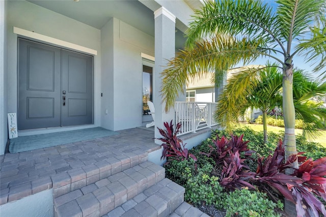 doorway to property with a porch and stucco siding