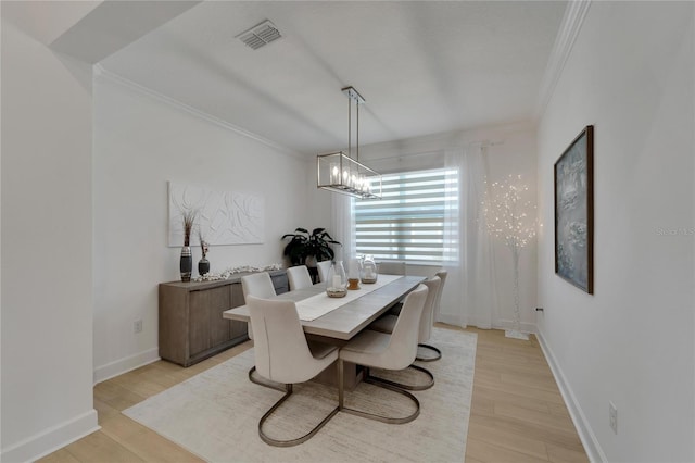 dining space featuring ornamental molding, a chandelier, light wood-style floors, and baseboards