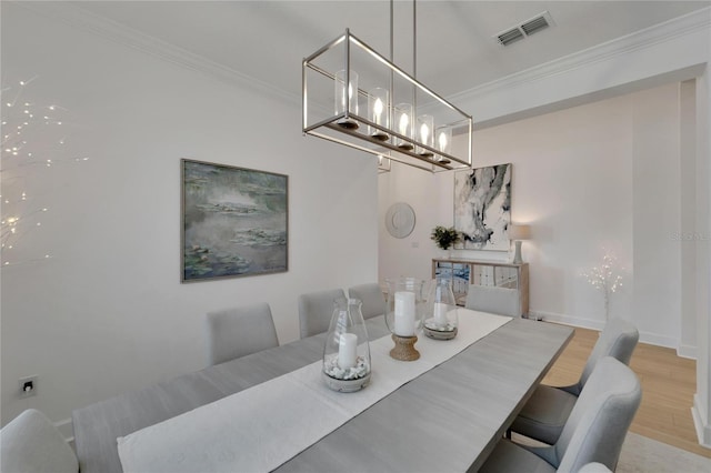 dining room with wood finished floors, crown molding, a chandelier, and baseboards