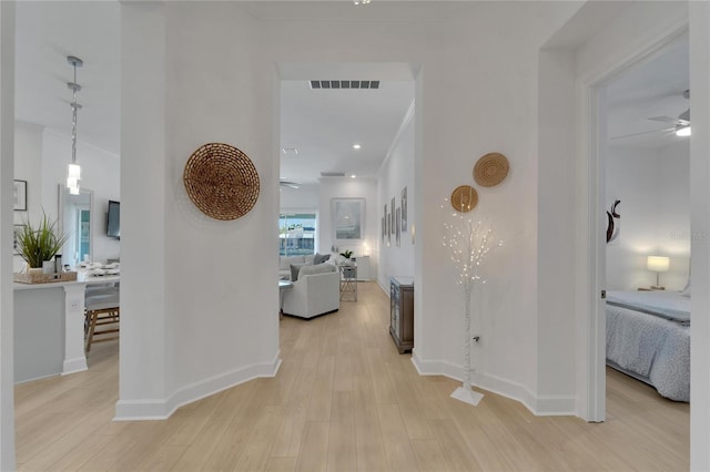 corridor with light wood finished floors, baseboards, and crown molding