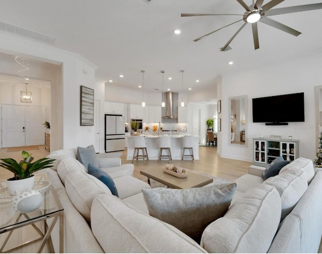 living area featuring visible vents, light wood-style flooring, a ceiling fan, and recessed lighting