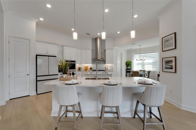 kitchen featuring wall chimney range hood, white appliances, decorative backsplash, a kitchen bar, and crown molding