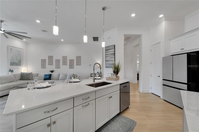 kitchen featuring a sink, freestanding refrigerator, stainless steel dishwasher, open floor plan, and crown molding