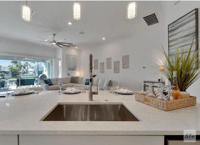 kitchen featuring open floor plan, a sink, decorative light fixtures, light stone counters, and recessed lighting