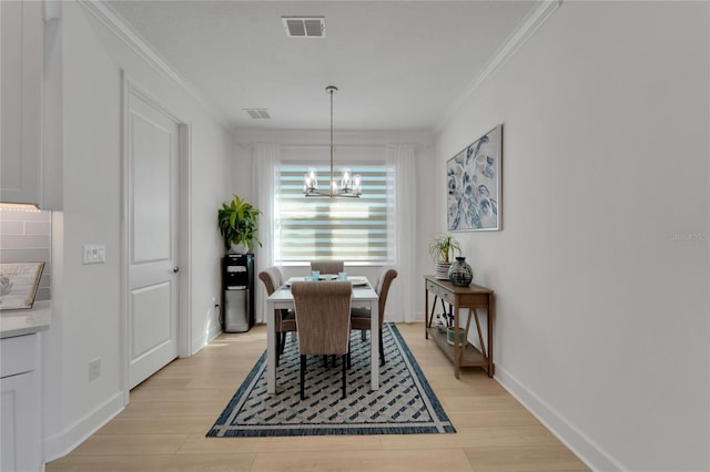 dining space featuring a chandelier, light wood-style floors, crown molding, and baseboards