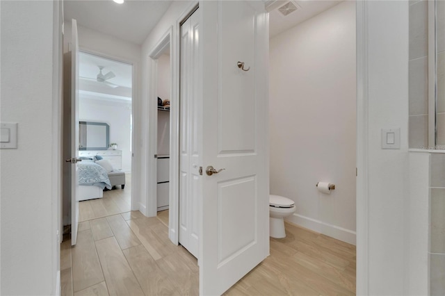 ensuite bathroom featuring toilet, baseboards, and wood finished floors