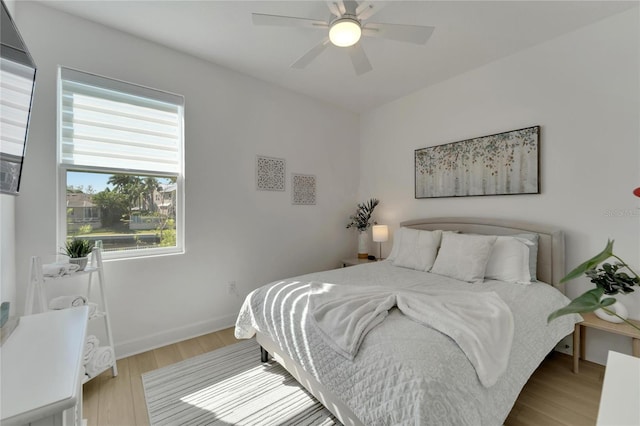 bedroom with wood finished floors, baseboards, and a ceiling fan