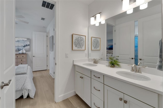 ensuite bathroom with double vanity, baseboards, and wood finished floors