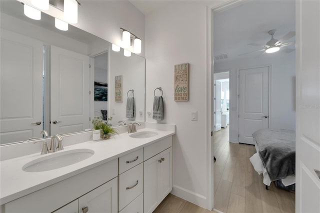 ensuite bathroom with baseboards, double vanity, and a ceiling fan