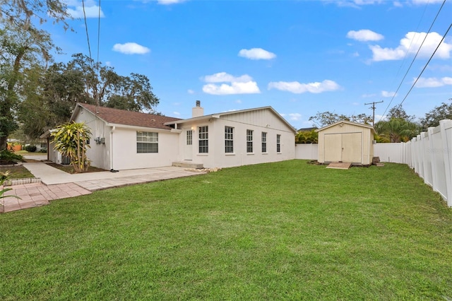 rear view of property with a lawn, a storage unit, and a patio