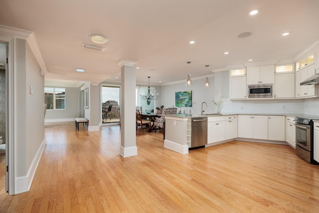 kitchen featuring white cabinets, stainless steel appliances, hanging light fixtures, and crown molding