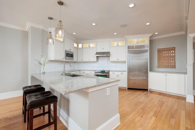 kitchen featuring kitchen peninsula, sink, pendant lighting, built in appliances, and white cabinetry