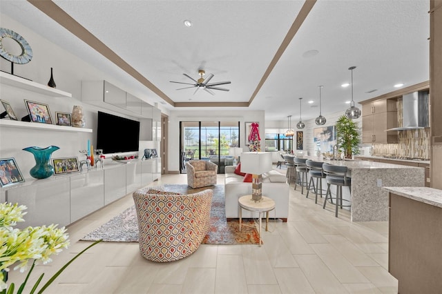 tiled living room featuring a textured ceiling, a tray ceiling, and ceiling fan