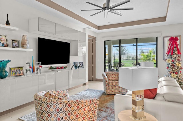 living room with a raised ceiling and ceiling fan