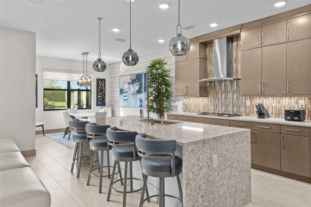 17702 Cresswind Ter, Bradenton, FL 34211 - kitchen featuring wall chimney range hood, a sink, stainless steel gas cooktop, recessed lighting, and light stone counters