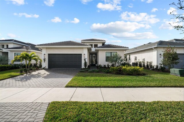 17702 Cresswind Ter, Bradenton, FL 34211 - prairie-style home with decorative driveway, a garage, cooling unit, stucco siding, and a front lawn
