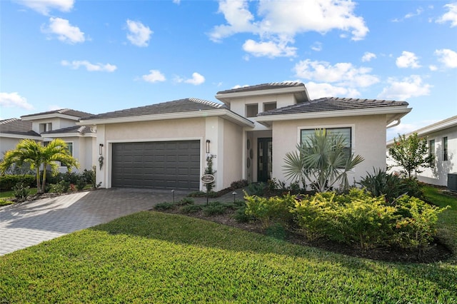 17702 Cresswind Ter, Bradenton, FL 34211 - prairie-style house with an attached garage, decorative driveway, a front yard, stucco siding, and central AC