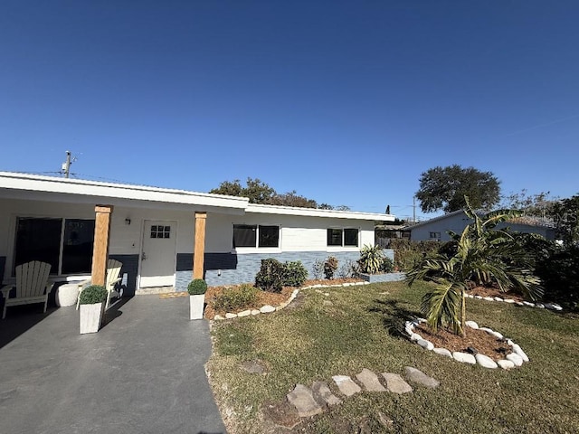 single story home featuring covered porch and a front lawn