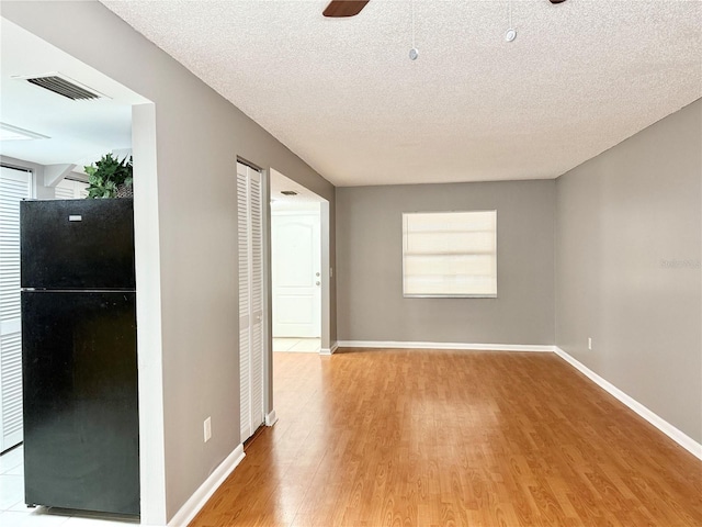 unfurnished room with ceiling fan, light hardwood / wood-style flooring, and a textured ceiling