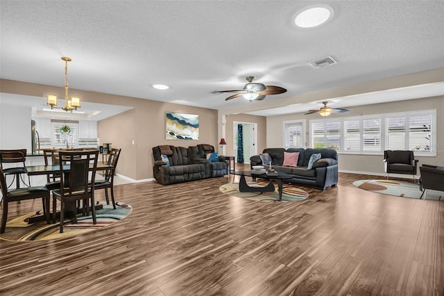 living room featuring a textured ceiling, ceiling fan with notable chandelier, and hardwood / wood-style flooring