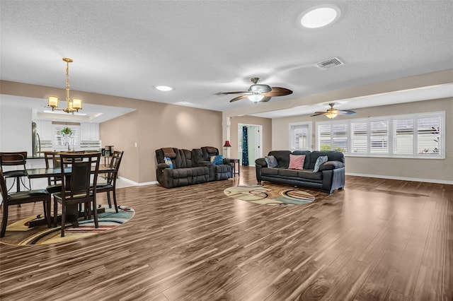 living room with ceiling fan with notable chandelier, dark wood-type flooring, a textured ceiling, and sink