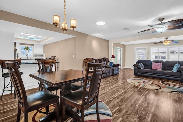 dining space with ceiling fan with notable chandelier, hardwood / wood-style flooring, and sink